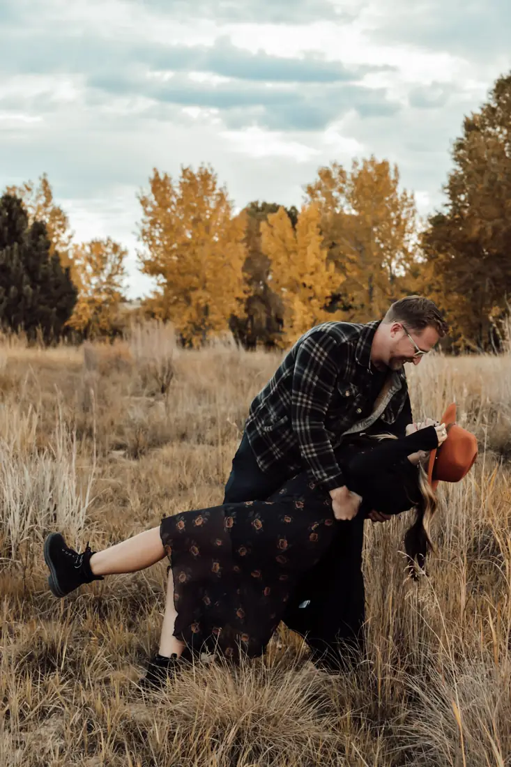 Couple dancing in an autumn field, he dips her