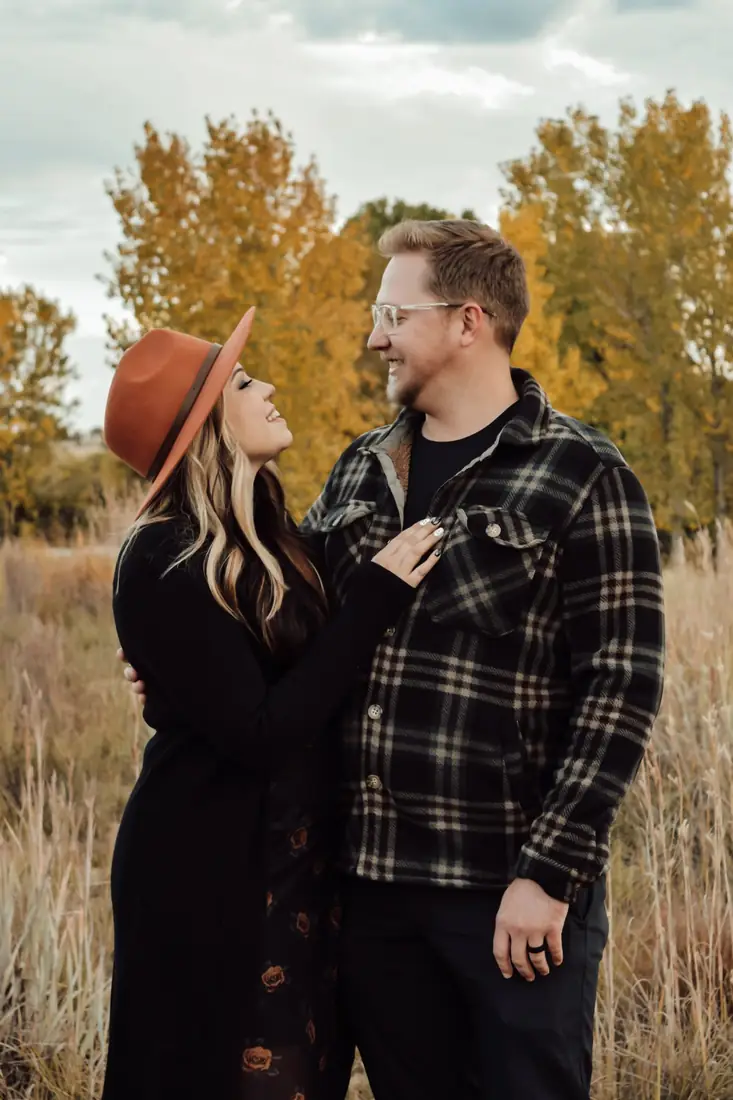Couple smiling at each other among golden autumn trees